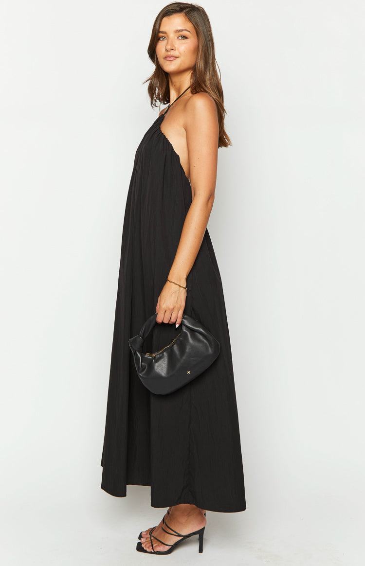 Side view of a black halter neck maxi dress showing the deep armhole and relaxed, flowy silhouette
