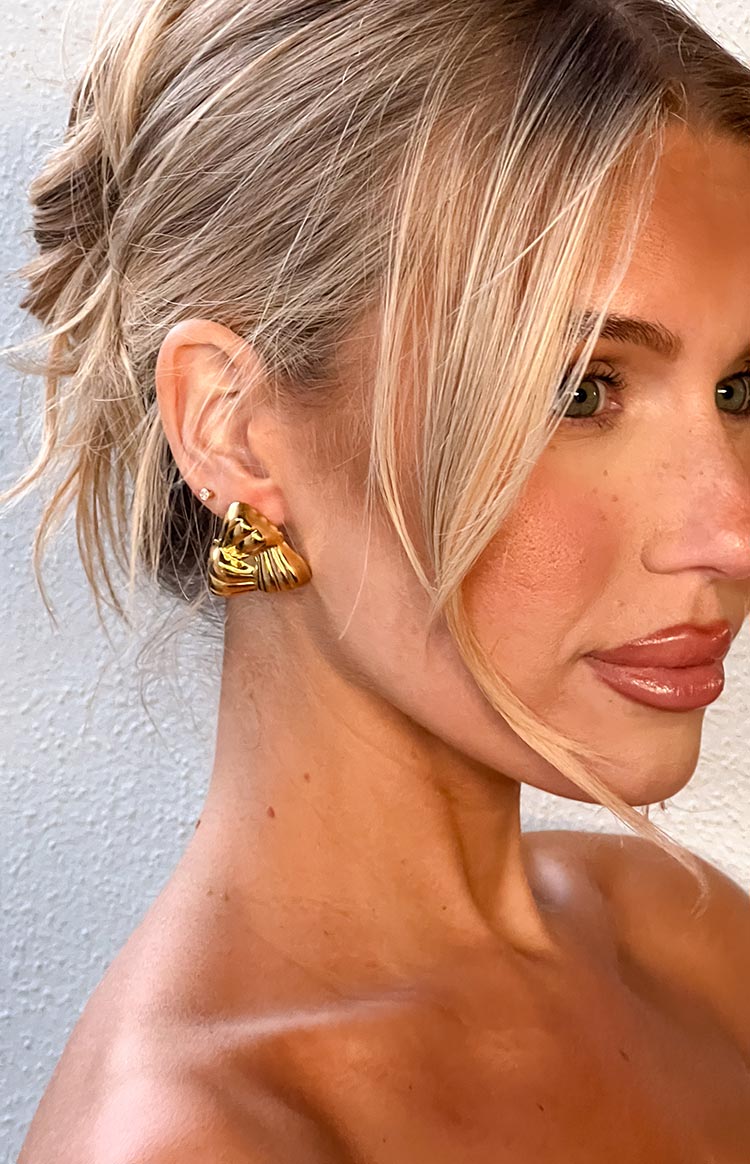 Side profile of a gold textured triangular stud earring with a pleated sculptural design