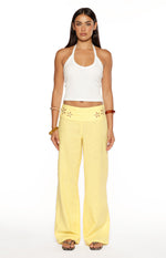Front view of yellow wide-leg pants with a high waist and floral cutouts on the waistband