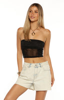 Woman wearing light acid wash denim shorts and a grey bikini top a perfect Summer Festival outfit