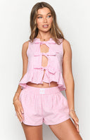 Close up of girl in a pink gingham top and matching pink shorts.