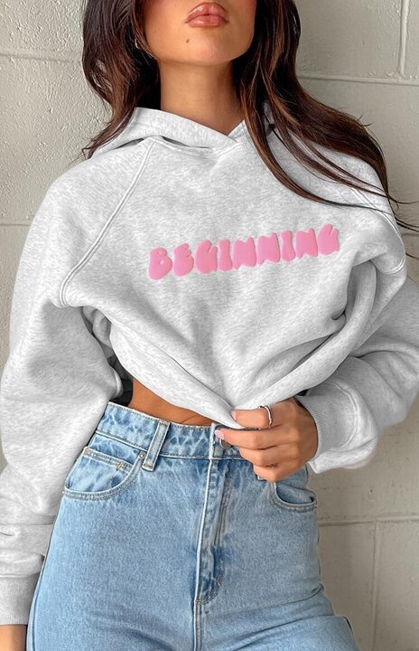 Close-up of the grey marl hoodie with pink bubble text "BEGINNING" on the chest and raglan sleeves