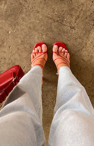 Overhead view of strawberry red square toe heels with thin criss-cross straps across the foot