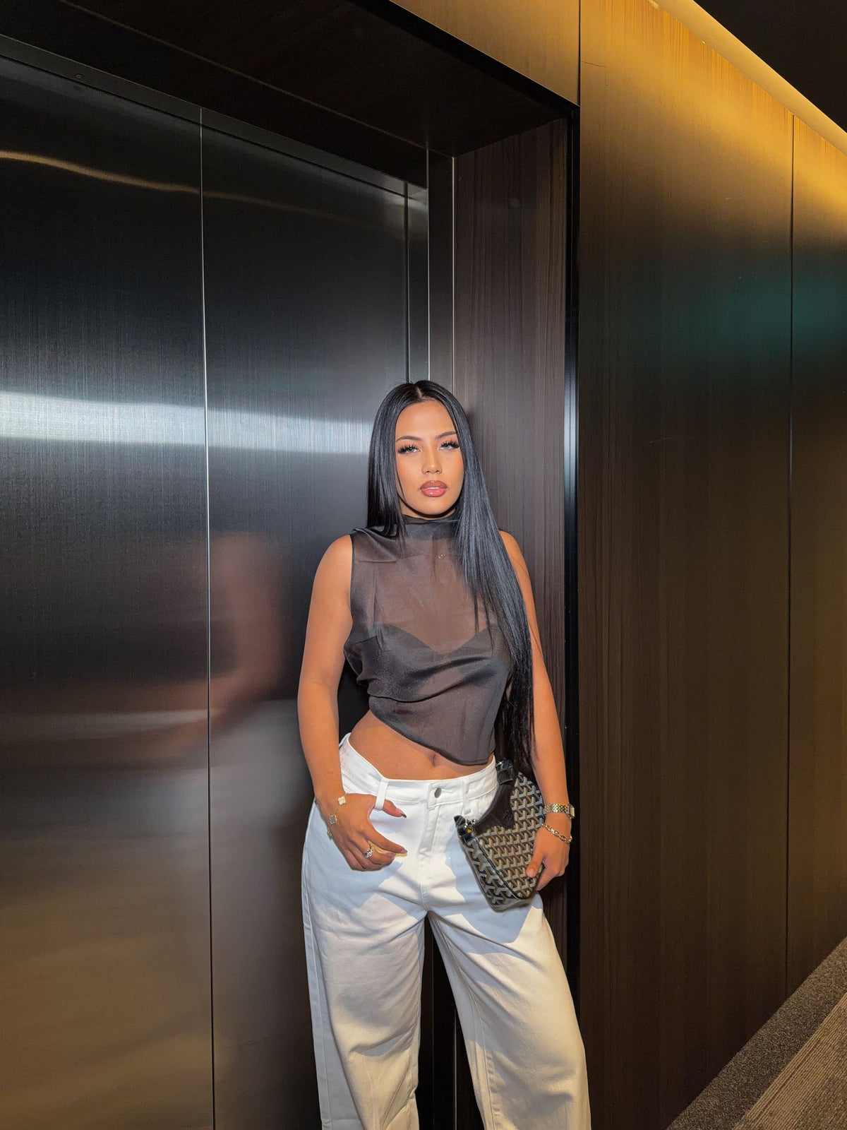 Black sheer high neck sleeveless top with a solid underlayer and an asymmetrical cropped hem