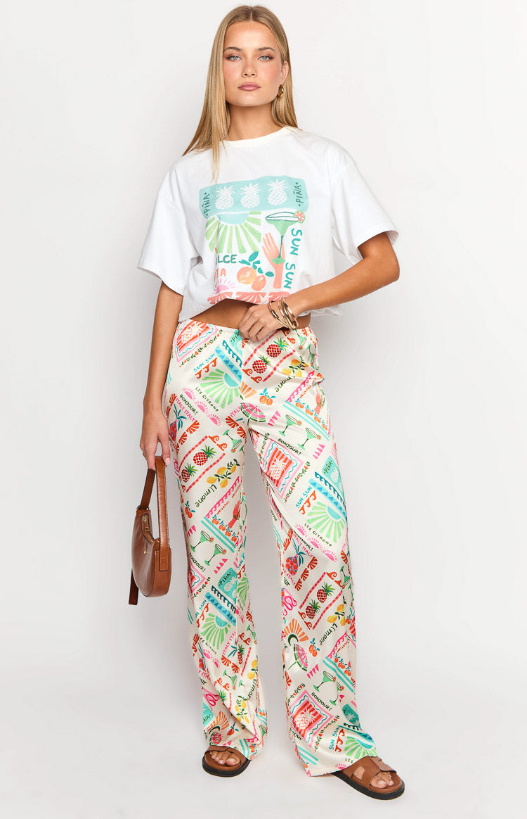 Cream wide-leg pants with a colourful Dolce Vita print featuring pineapples, cocktails, and lemons