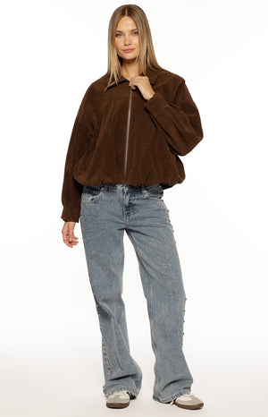 Our model wearing an oversized cropped jacket in a deep brown corduroy fabric. This jacket features a wide collar a full silver zipper and a gathered elasticized hemline that creates a blouson shape.