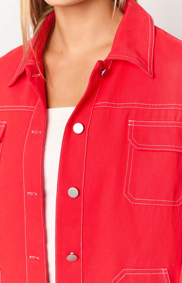 Close-up of the red denim jacket's white contrast stitching, silver snap buttons, and chest pocket