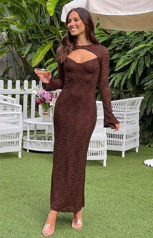 Brunette model wearing brown lace maxi dress holding a drink outdoors. 