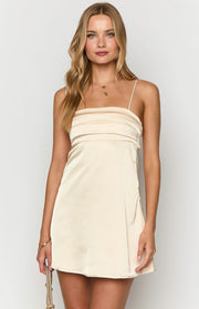 Close-up front view of a cream satin mini dress with a straight neckline and pleated bust