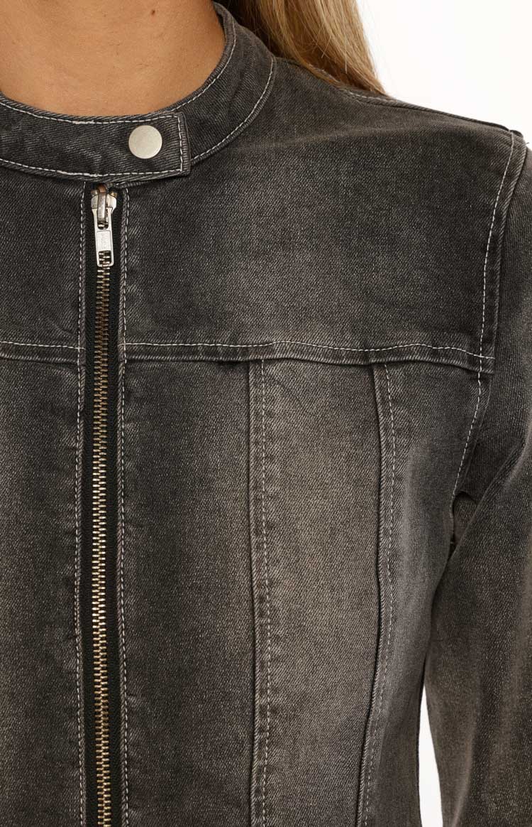 Close-up of the washed black denim biker jacket showing the band collar, silver zipper, and white contrast stitching