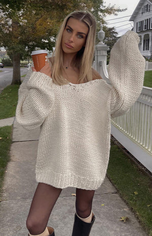 Cream chunky knit sweater with an off-shoulder neckline, oversized fit, and voluminous long sleeves