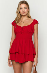 Red playsuit with an elasticated off-shoulder neckline, short ruffled sleeves, shirred waist, and tiered shorts