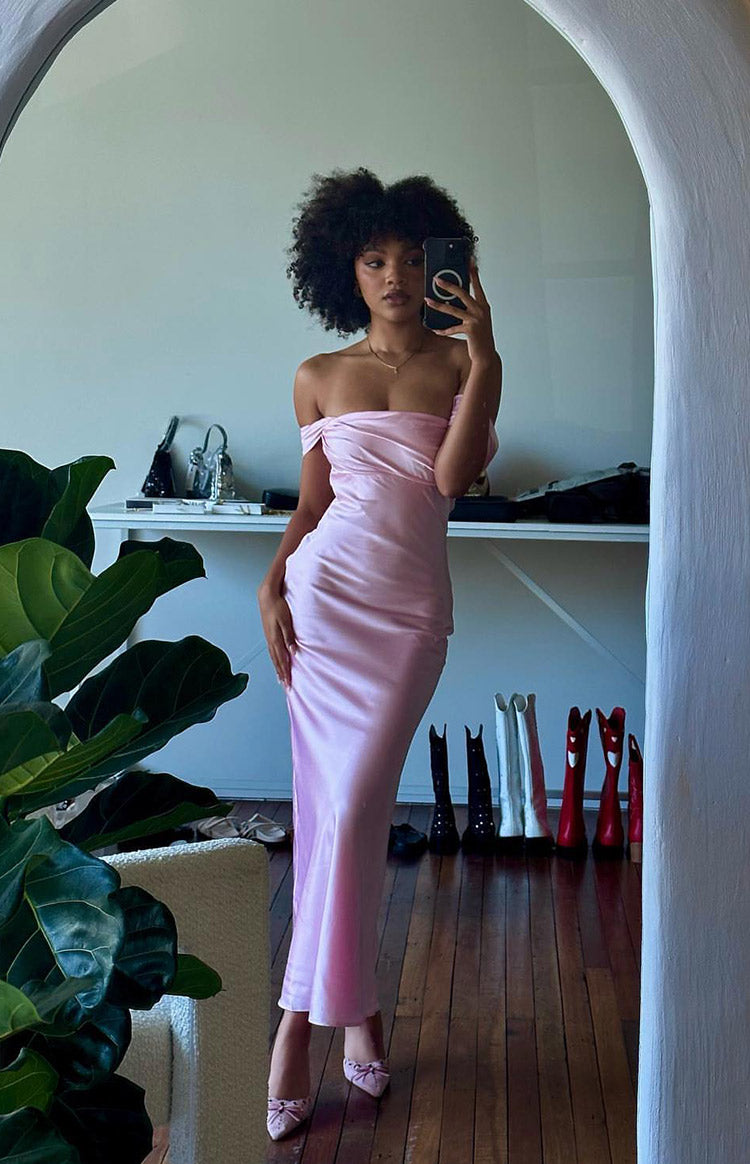Full length view of a light pink satin off-shoulder maxi dress with a draped neckline and fitted silhouette