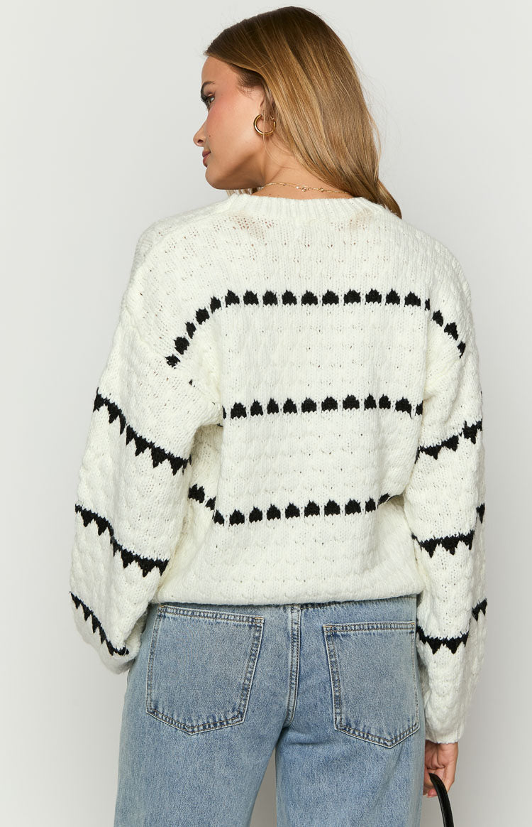 Back view of a white chunky knit sweater with black heart stripe pattern and round neckline