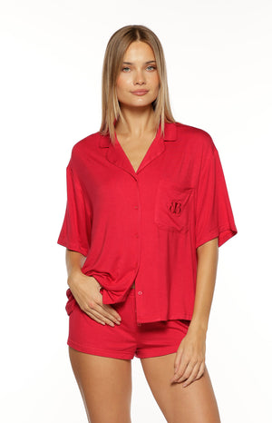 Our model is wearing short fitted pajama shorts in a solid red knit fabric. These shorts feature a decorative button fly detail at the center front and an elasticized waistband. A matching red short-sleeve button-down perfectly wear with matching pajama top set.