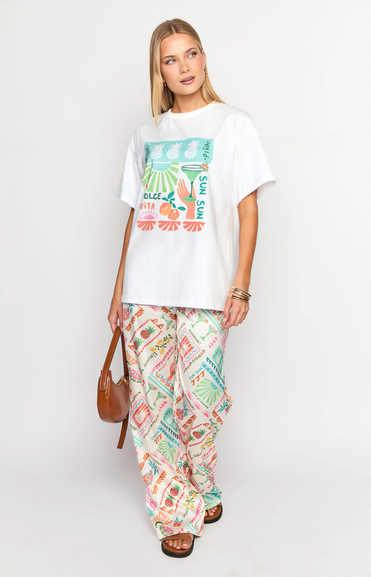 White oversized crew neck short sleeve tee with a vibrant 'Dolce Vita' graphic print of pineapples and cocktails