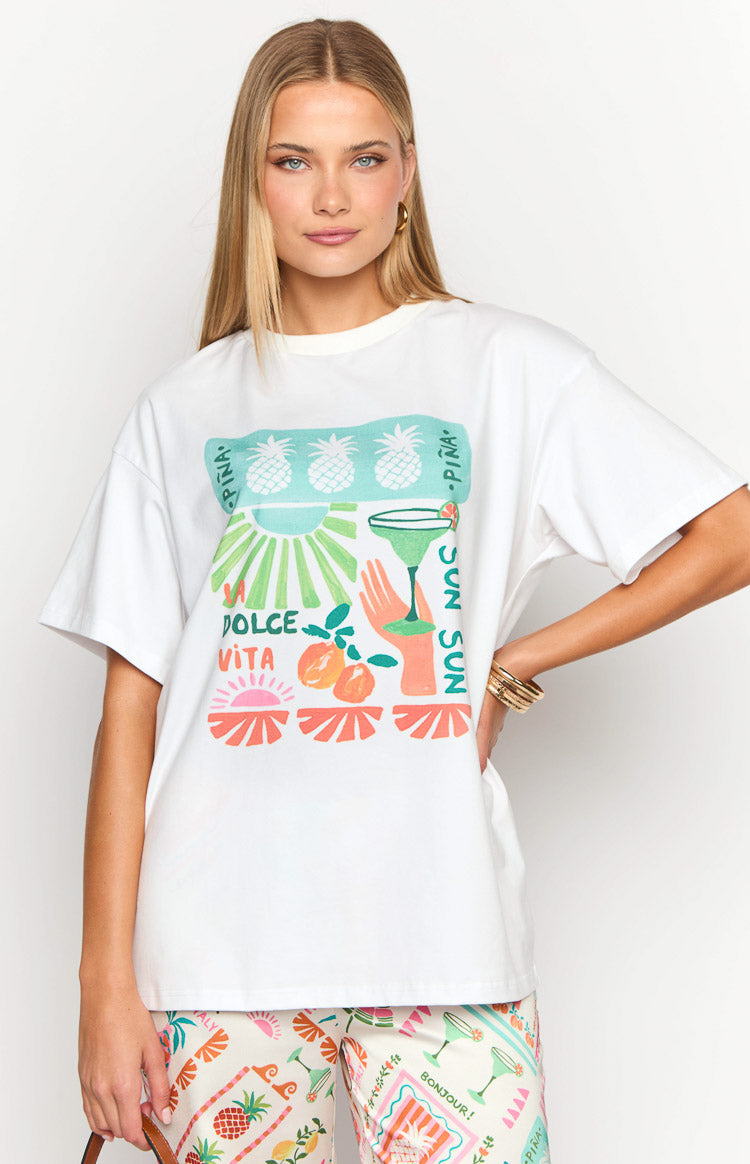 White oversized tee with a vibrant graphic print of pineapples, a cocktail, oranges, and 'Dolce Vita' text