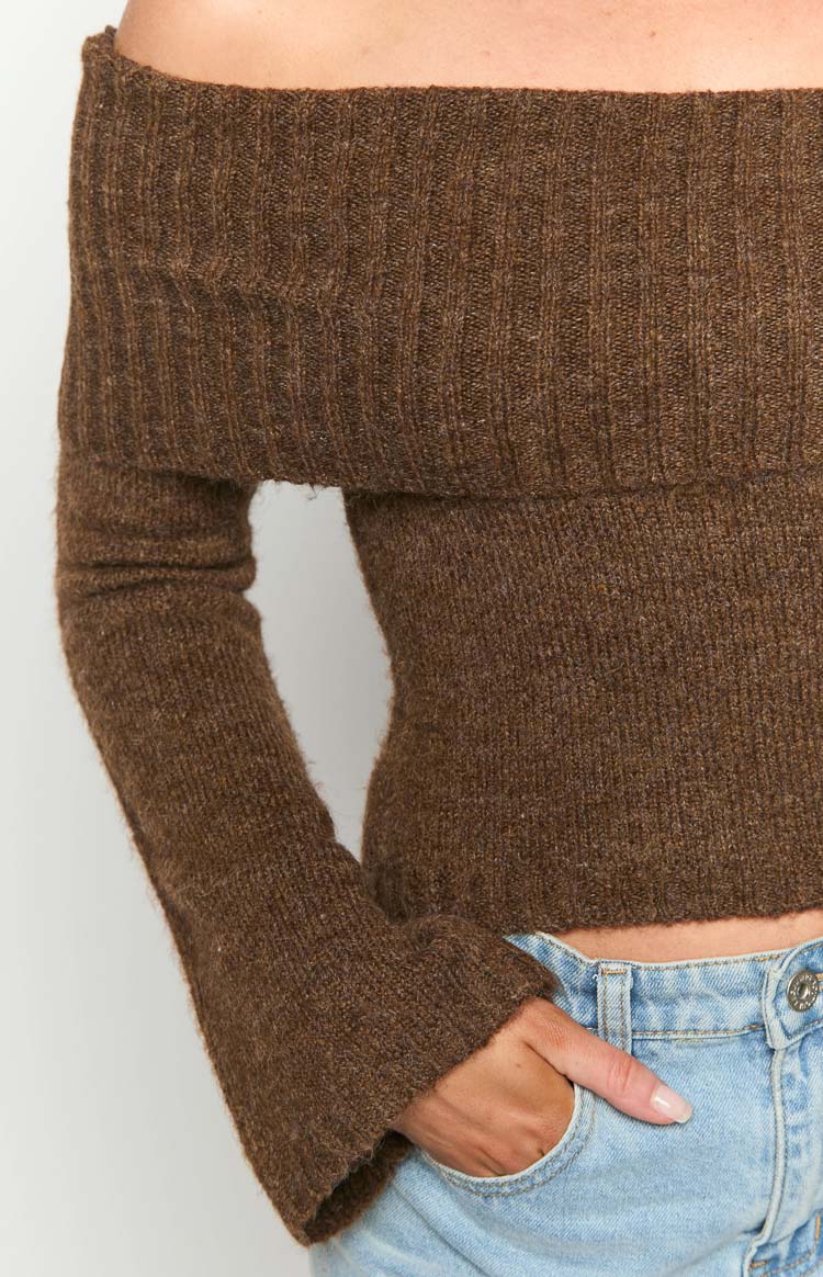 Close-up of the brown ribbed knit off-shoulder sweater showing the fitted waist and flared cuffs