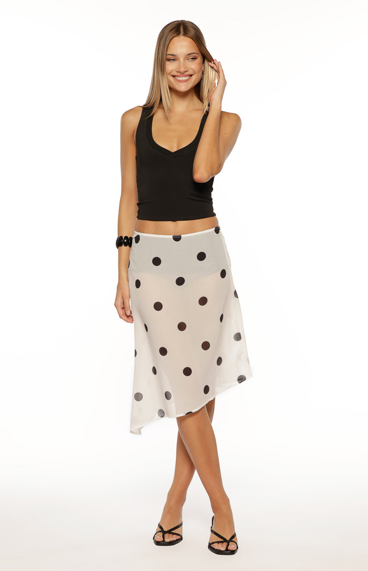 Flowy white sheer midi skirt with black polka dots and an asymmetrical hem