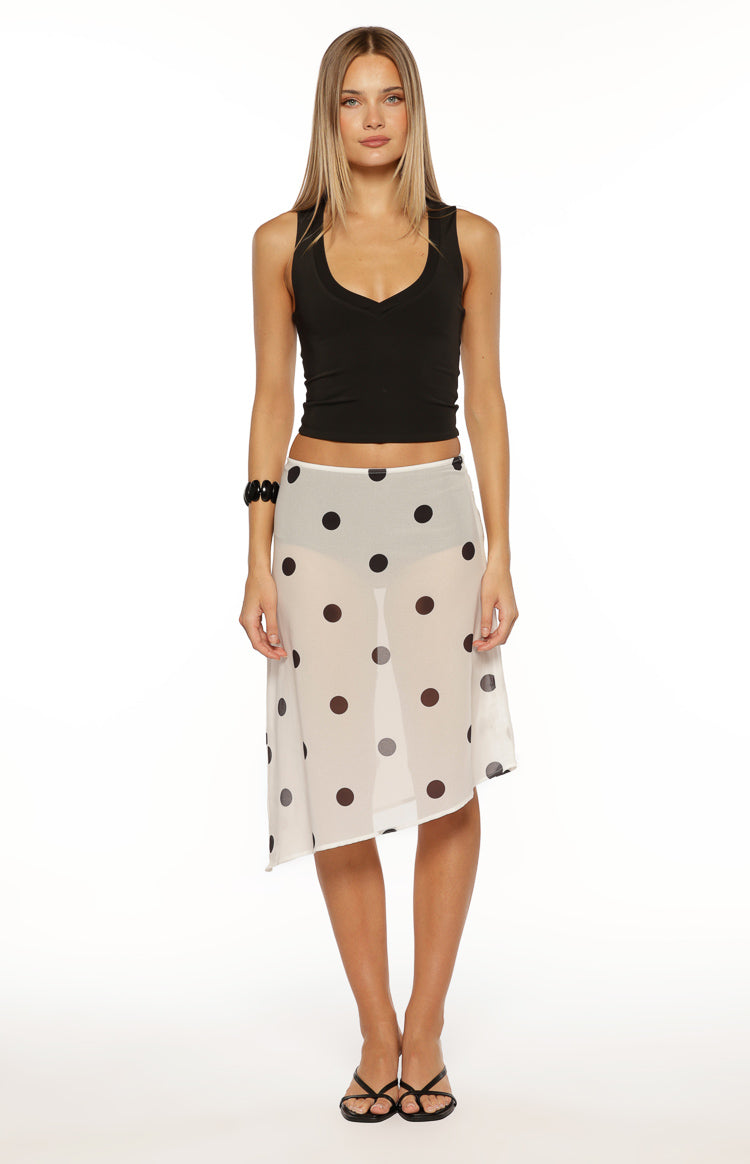 Full length view of a white sheer midi skirt with black polka dots and an asymmetrical hem