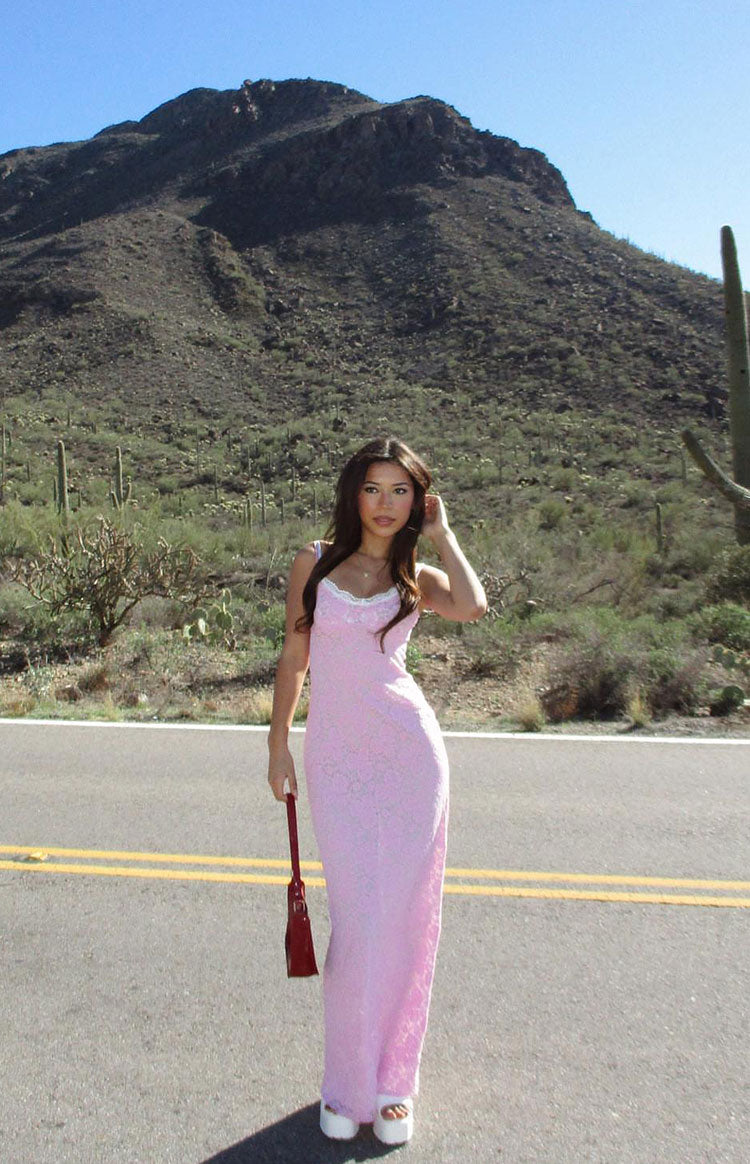 Full length view of a pink lace maxi dress with a fitted silhouette and white lace trim on the neckline