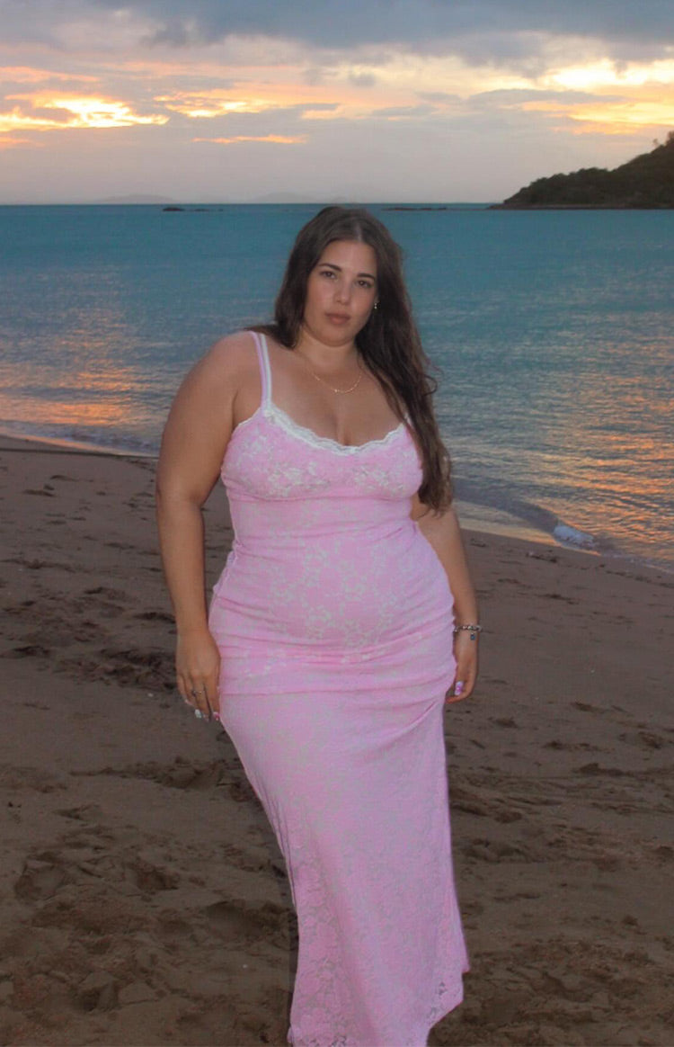 Front view of a fitted pink lace maxi dress with white lace trim on the V-neckline and thin straps