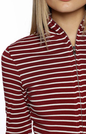 A tightly cropped close-up focuses on the shoulder and chest our model wearing a fitted long-sleeve knit sweater. This sweater features a pattern of thin white horizontal stripes over a deep burgundy base color. It has a high mock-neck collar and a prominent silver zipper running down the center front.