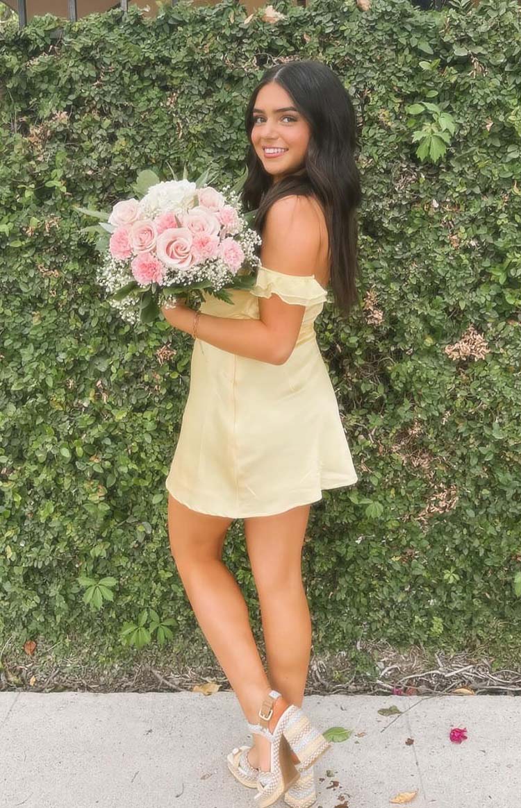 Side view of a yellow satin mini dress with off-shoulder ruffled sleeves and a flowing A-line skirt