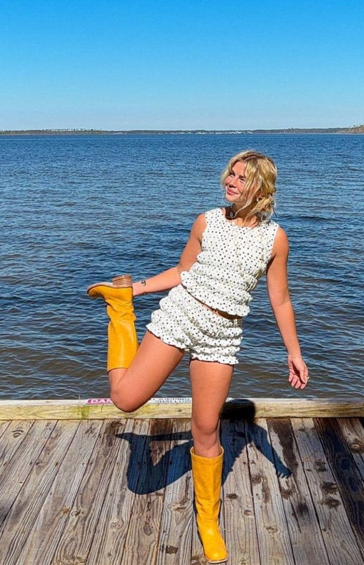 Front view of white polka dot shorts with a ruffled hem and gathered elasticated waist