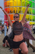 Front view of a black sheer high neck sleeveless crop top with a loose, draped hem