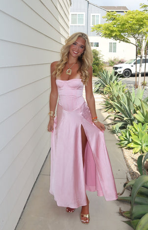 Full front view of a pink satin strapless corset maxi dress with a high thigh split