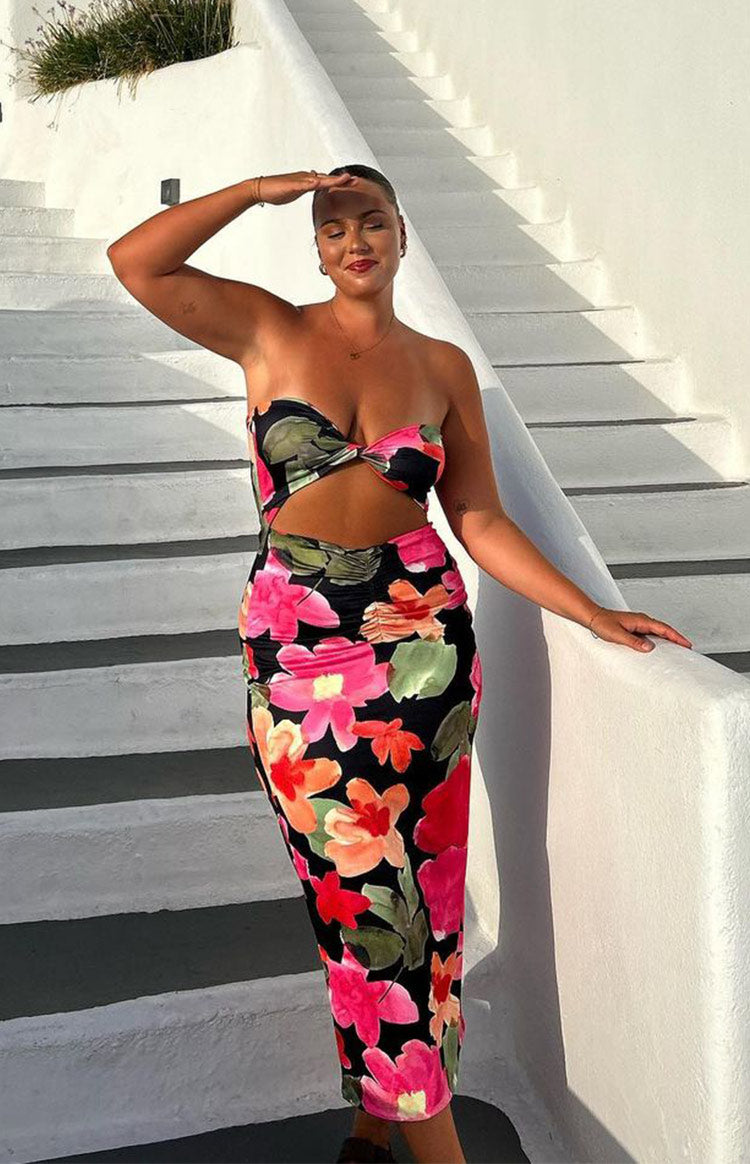 Front view of a black floral midi dress with a twisted strapless bust, side cutouts, and ruched skirt