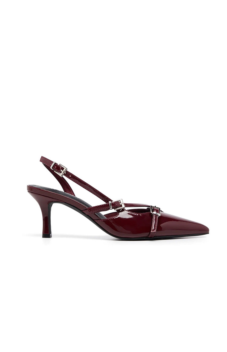 Side view of a deep red patent slingback heel with a pointed toe and three thin buckled straps across the vamp