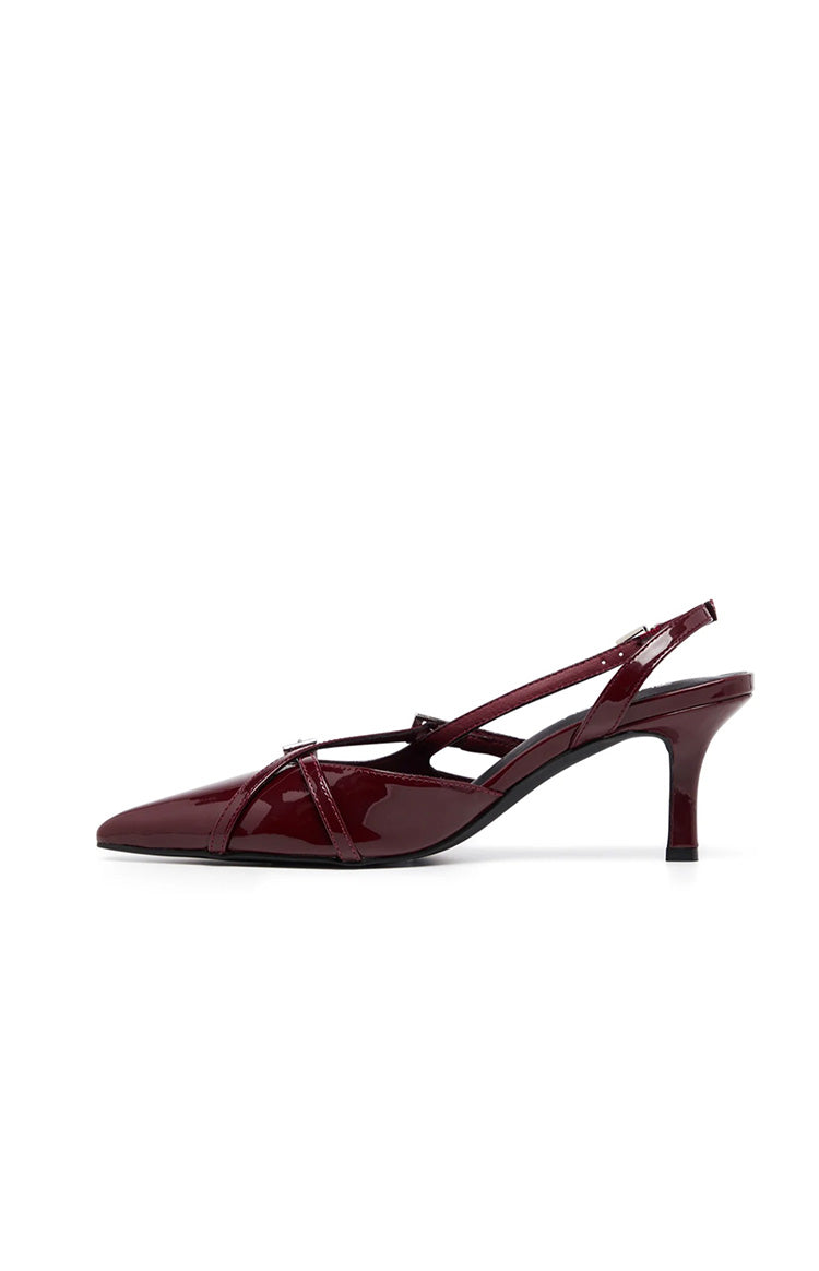 Side view of a red patent slingback heel with a pointed toe, criss-cross vamp straps, and a kitten heel