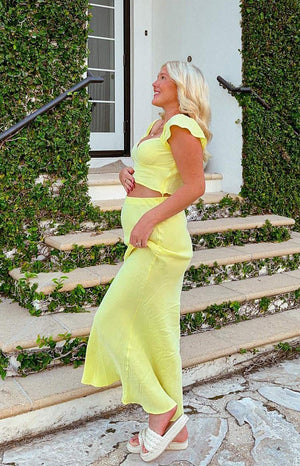 Side view of a flowing yellow maxi skirt with a relaxed fit and a subtle sheen