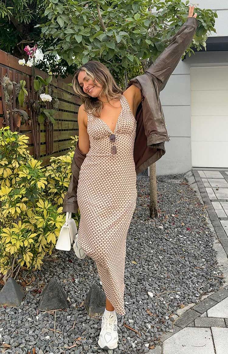 Full length view of a fitted beige maxi dress with a small brown geometric pattern and deep V-neck