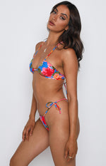 Side view of a blue floral triangle bikini top with red and pink flowers, halter neck, and tie-back straps