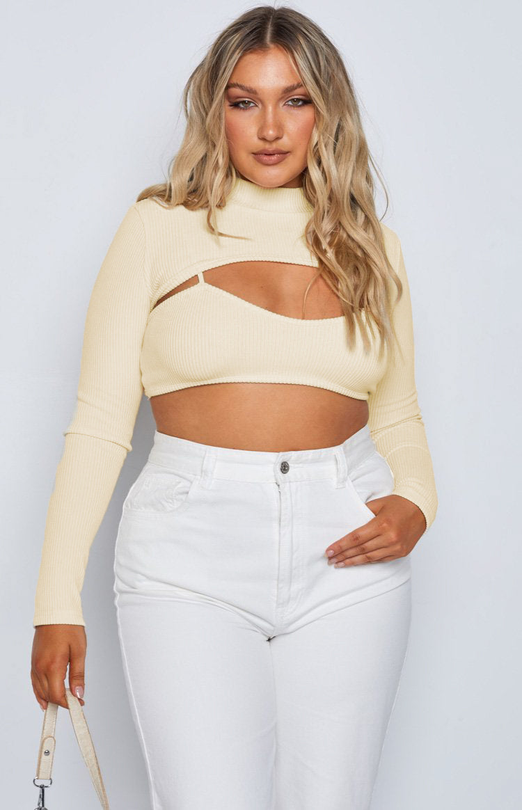 Cream ribbed Adventure Rib Top with a high neck, long sleeves, cropped fit, and a large chest cutout revealing a bralette