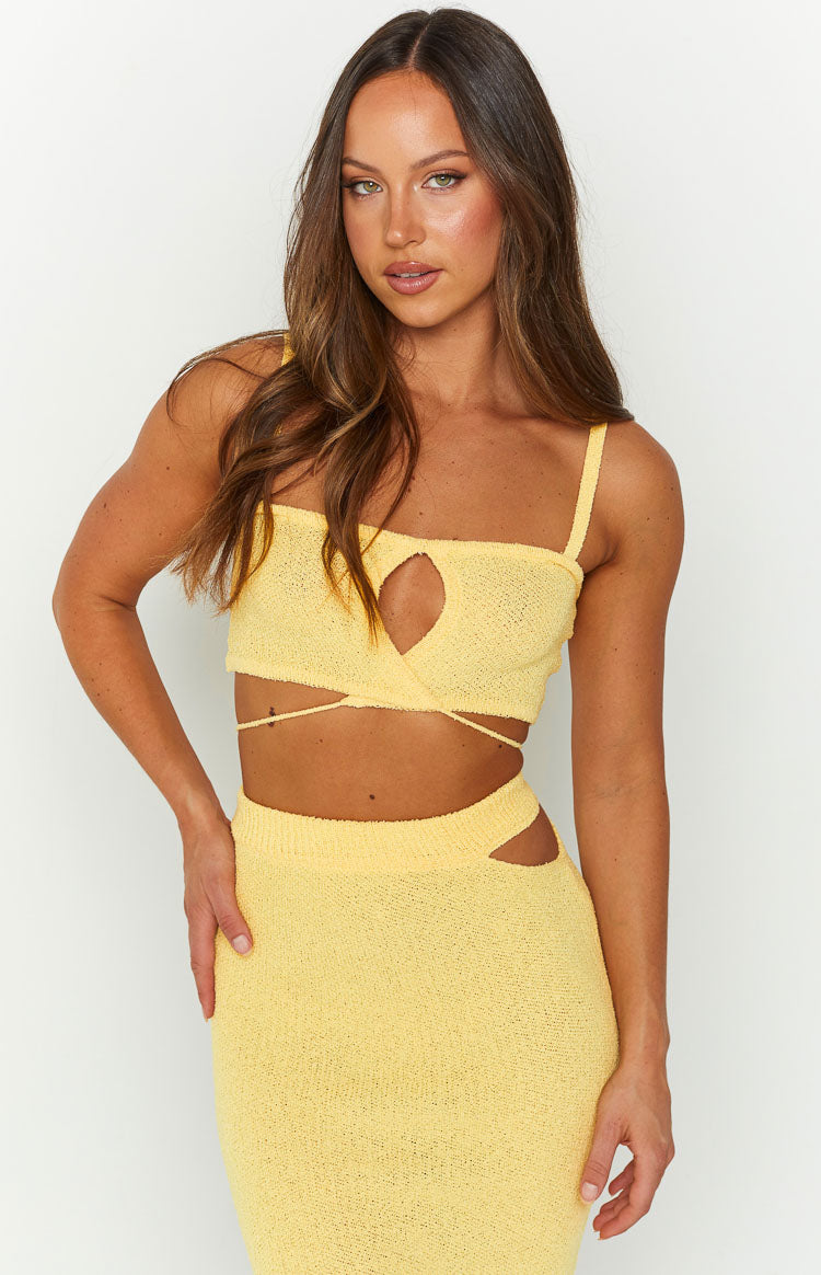 Close-up of a yellow knit crop top with thin straps, a front keyhole cutout, and wrap-around waist ties
