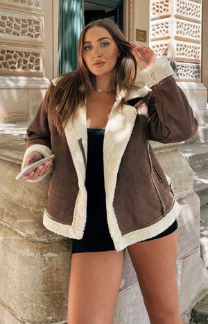 Brunette model wears brown jacket with white fleece lining.