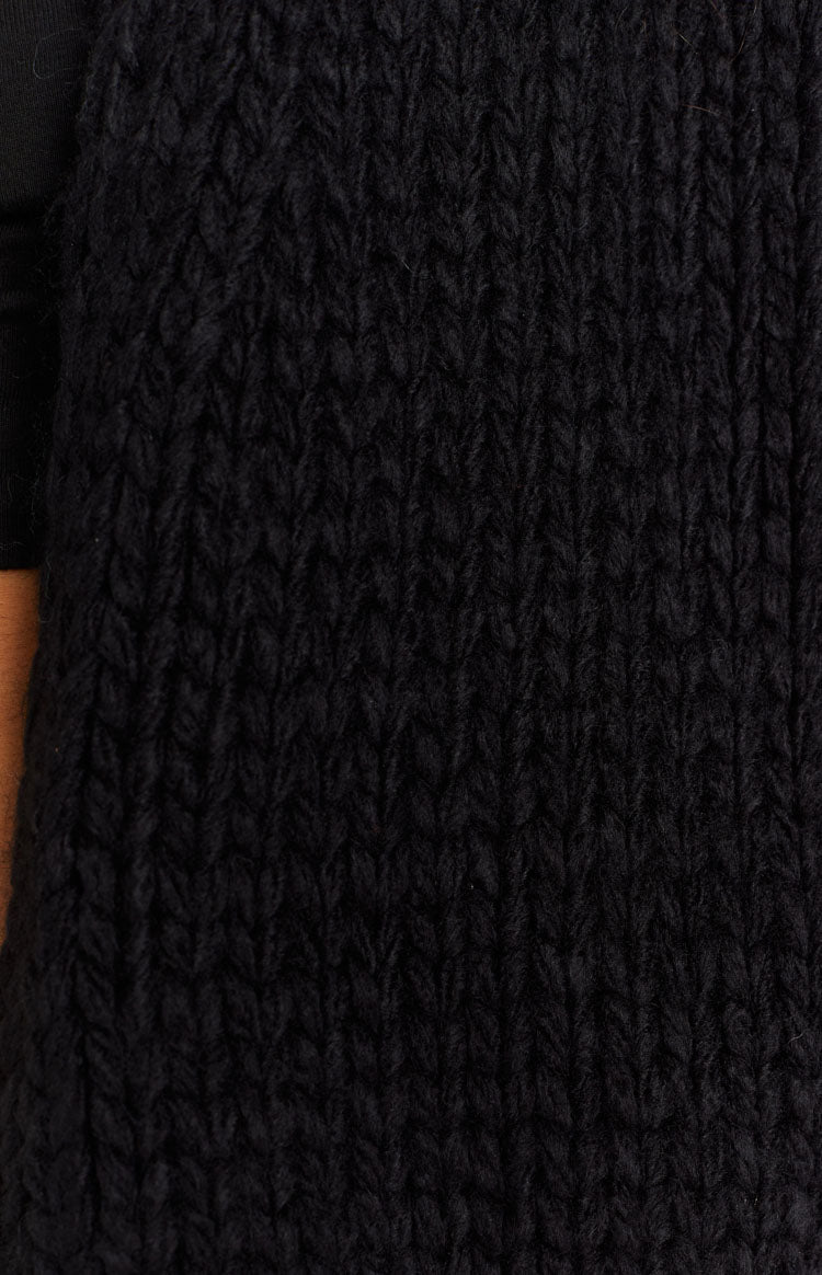 Detail shot of the black knit cardigan showing the thick, textured stitch pattern