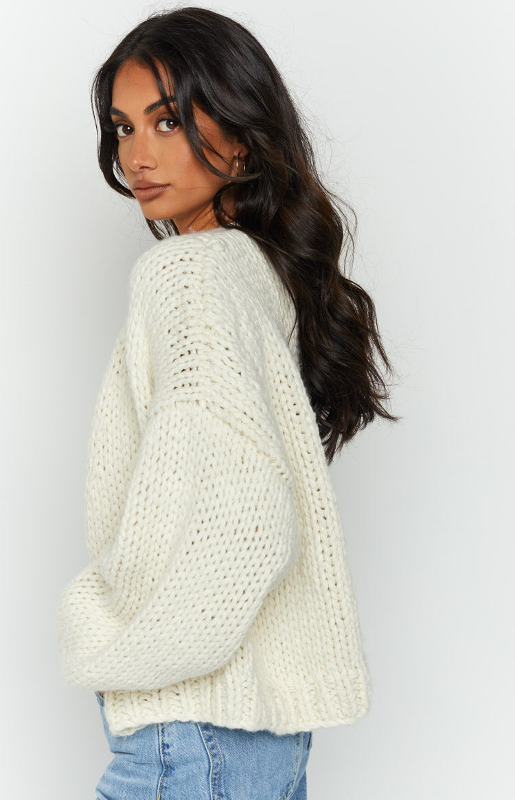 Side view of a cream chunky knit cardigan with dropped shoulders, voluminous long sleeves, and a thick ribbed texture