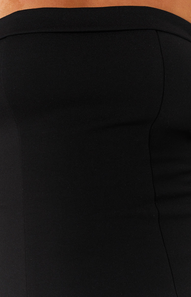 Close-up of the black fabric of the mini dress, showing a vertical seam and the smooth texture