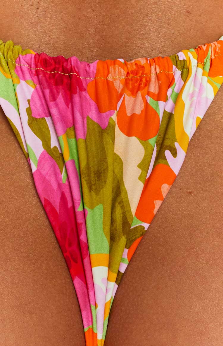 Close-up showing the ruched elasticated top edge and gold stitching of a floral print bikini bottom