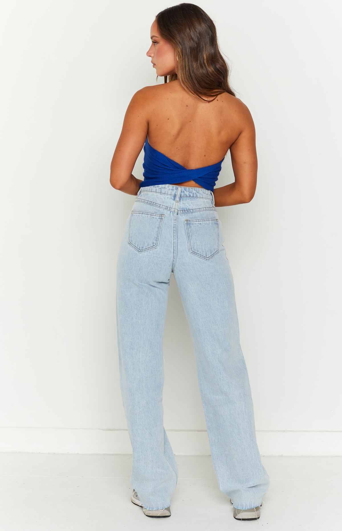 Rear view of light blue wide-leg jeans with back pockets and a frayed hem