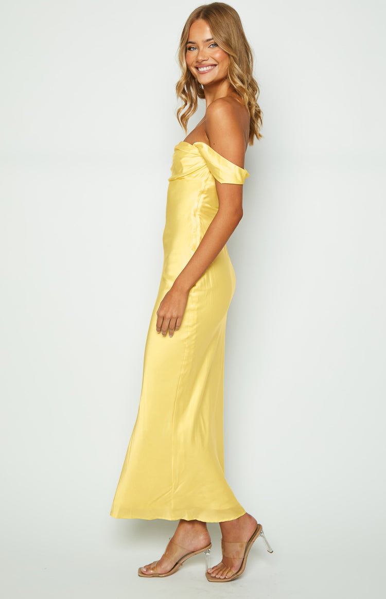 Side view of the light yellow off-shoulder maxi dress, highlighting the draped neckline and smooth satin fabric