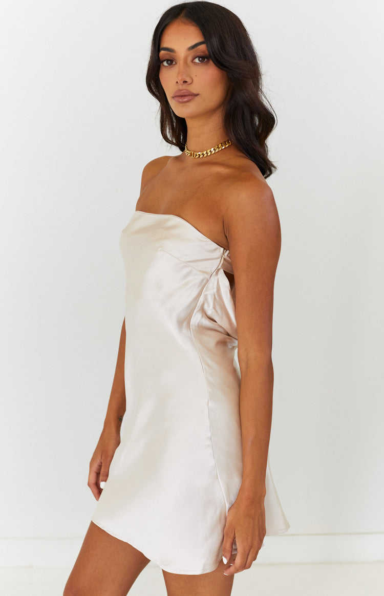 Side view of a cream satin strapless mini dress with a gathered and draped detail on the side bodice