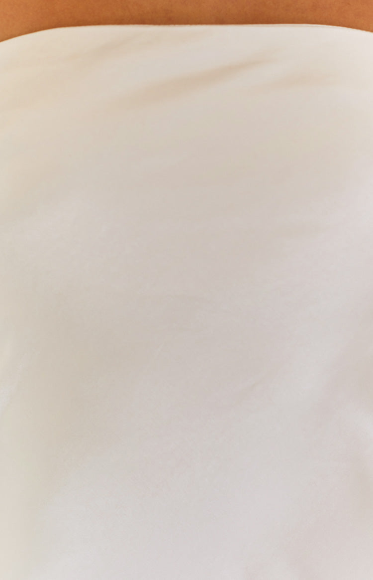 Close-up of the smooth cream fabric of the mini dress showing its soft texture and subtle drape