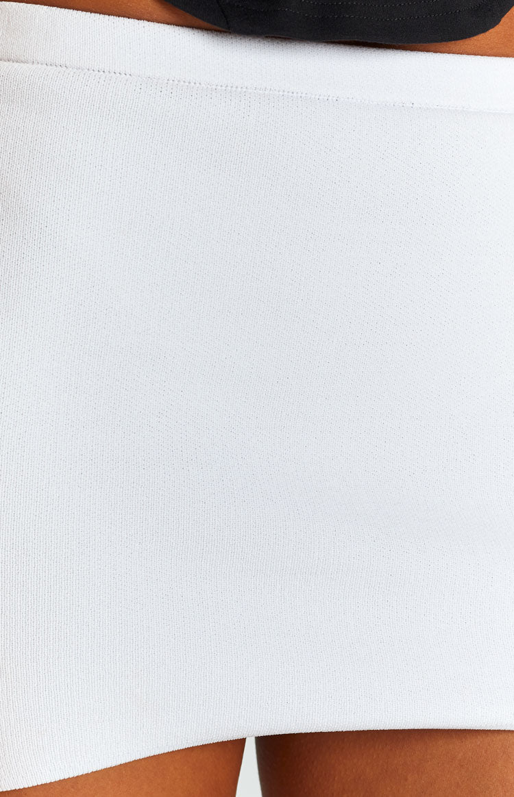 Close-up of the white knit fabric of the mini skirt, showing the subtle texture