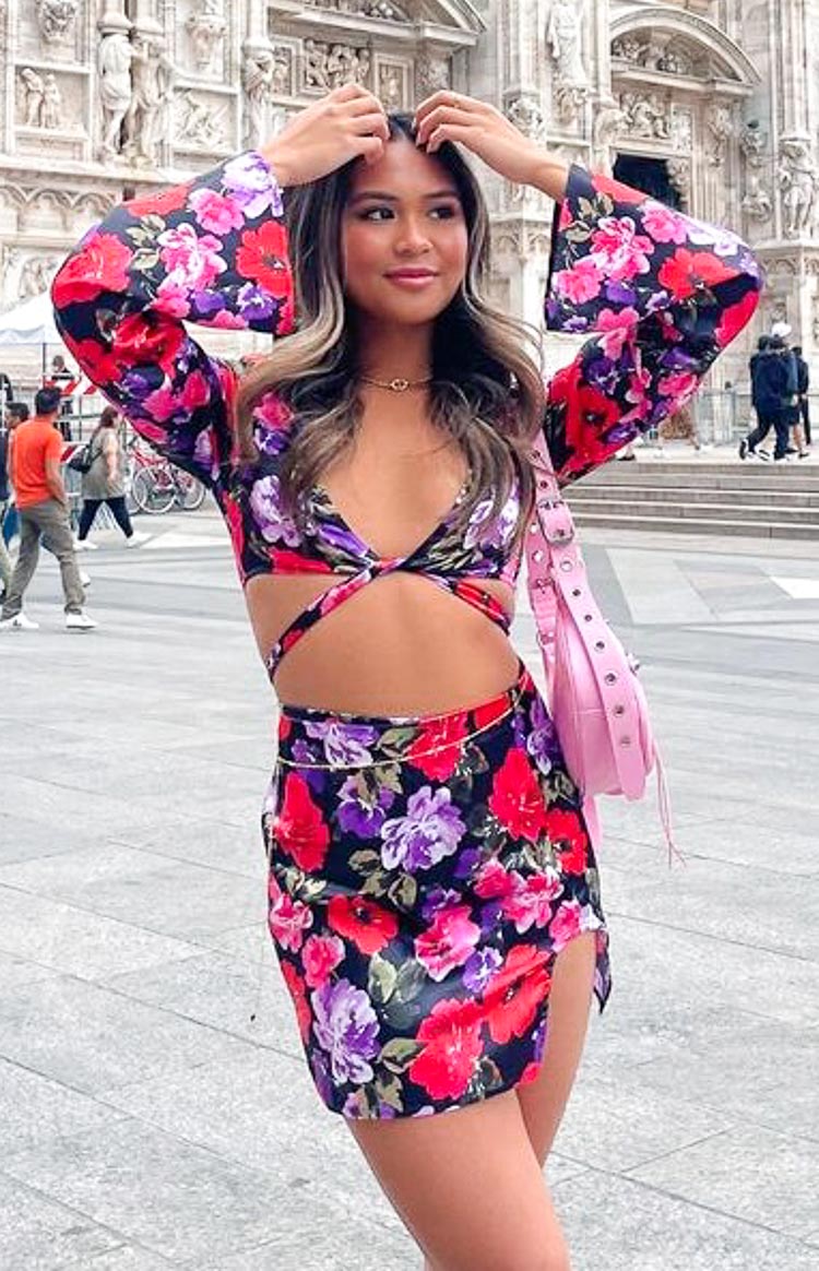 Black floral print wrap top with long bell sleeves, twisted front detail, and midriff cutouts